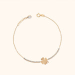 Gold-tone chain bracelet with a flat four-leaf clover centerpiece, rows of clear accents, and an extender with a teardrop-shaped charm.