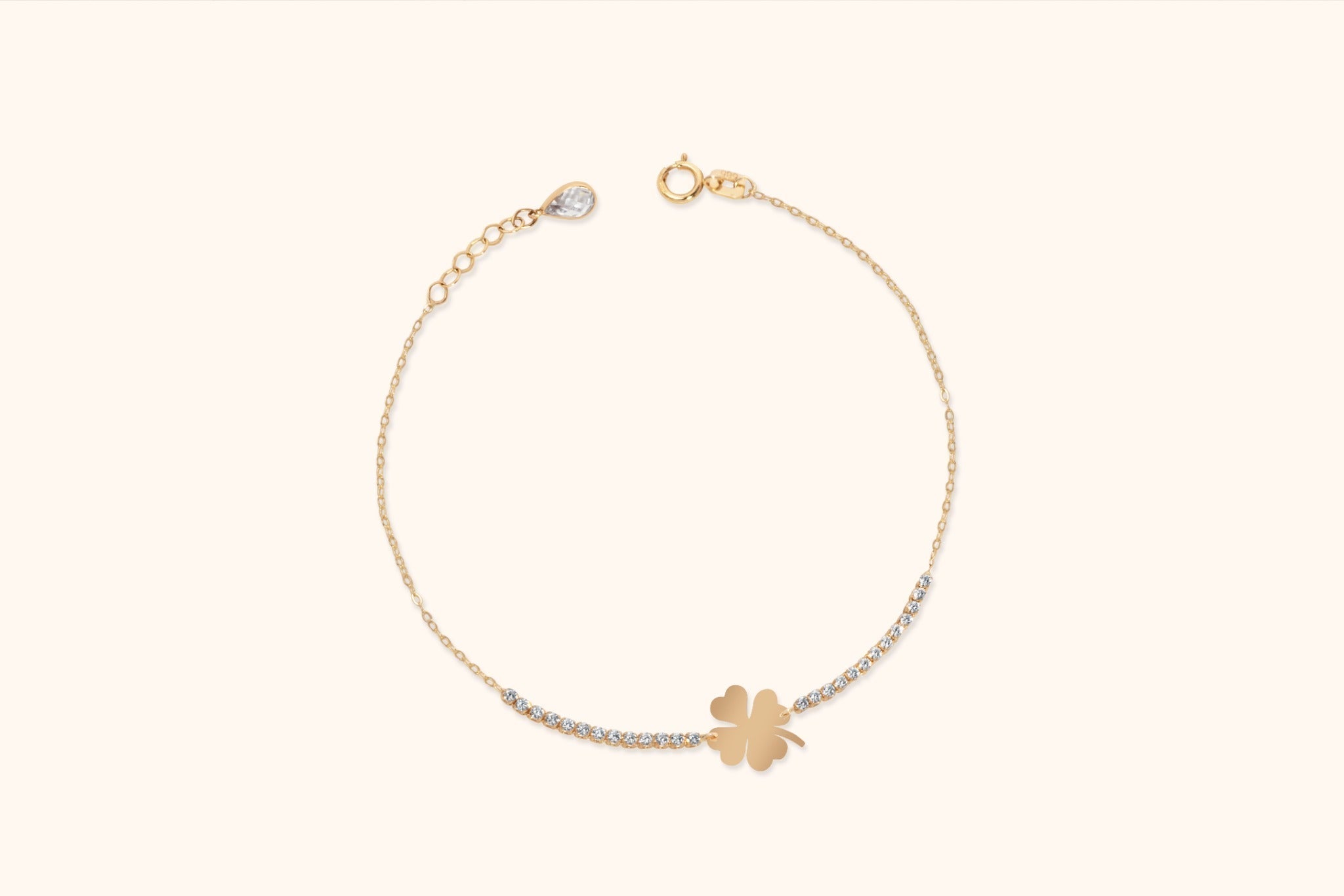 Gold-tone chain bracelet with a flat four-leaf clover centerpiece, rows of clear accents, and an extender with a teardrop-shaped charm.