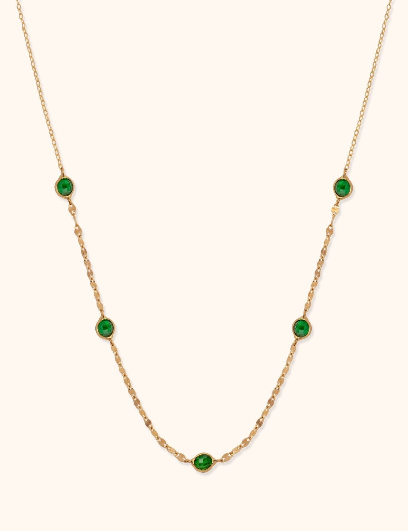 Gold-toned chain necklace with five faceted green accents in rounded settings and flat oval links along the lower section.