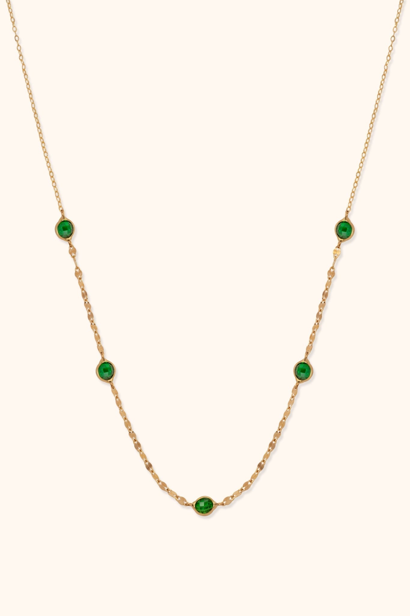 Gold-toned chain necklace with five faceted green accents in rounded settings and flat oval links along the lower section.