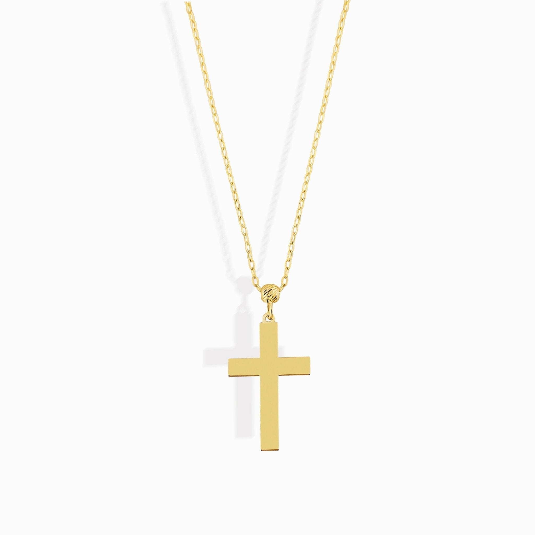 Gold-colored necklace with an oval-link chain, a textured bead, and a smooth, flat cross pendant on a white background.
