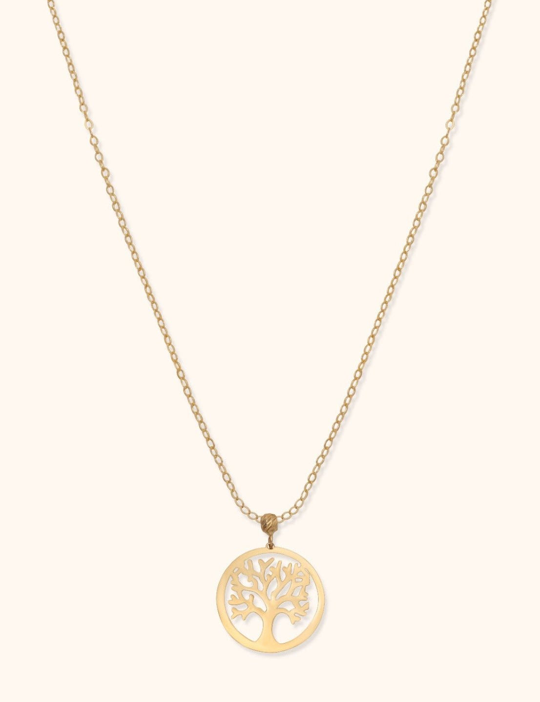 Gold-toned necklace with a fine oval-link chain and a circular pendant featuring an openwork tree on a cream background.