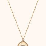 Gold-tone chain necklace with an oval pendant, rope-style border and teal-centered eye motif outlined in clear sparkling accents.