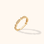 Gold-toned ring with alternating elongated and square settings, clear sparkling accents and beaded edges, shown at an angle.