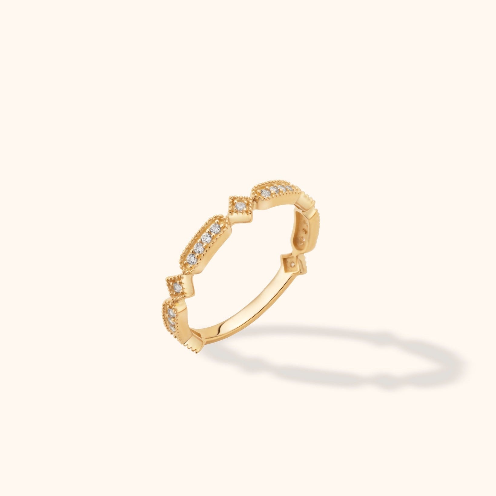 Gold-toned ring with alternating elongated and square settings, clear sparkling accents and beaded edges, shown at an angle.