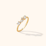 Gold-colored ring with a rope-textured band and clear rectangular, square and round stones, shown at an angle on a cream background.