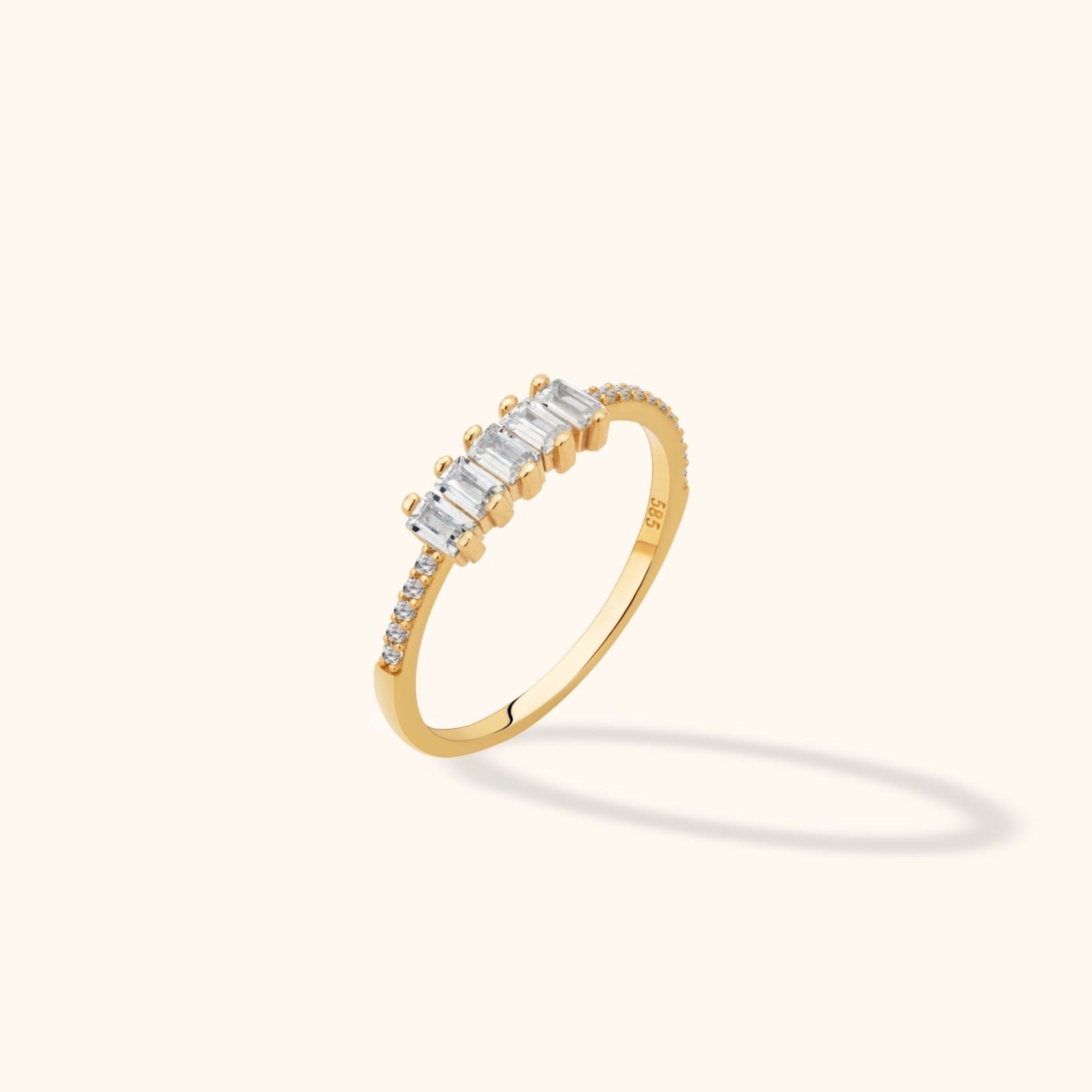 Gold-toned ring with five clear rectangular stones across the top and small round stones along both sides of a slim band.