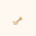 Gold-colored Aquarius symbol stud with a straight post and round flat back, shown diagonally on a cream background.