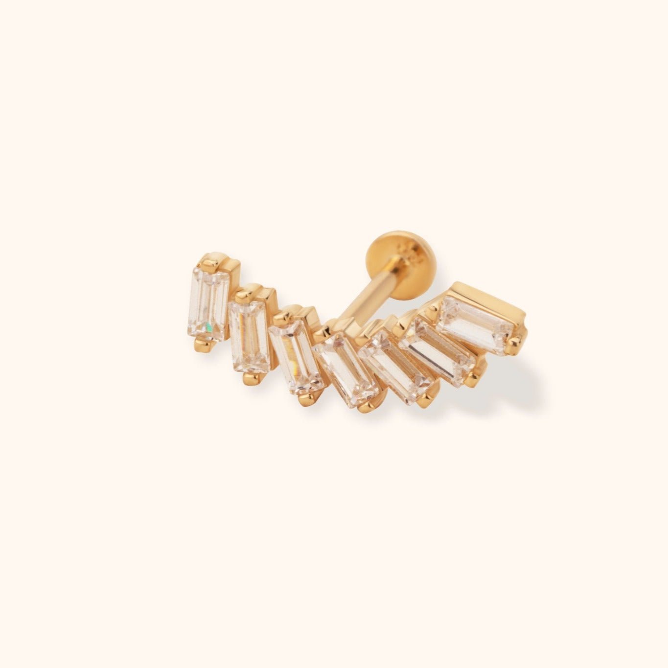 Gold-tone stud with clear rectangular stones arranged in a curved fan, a straight post and round flat back on a cream background.