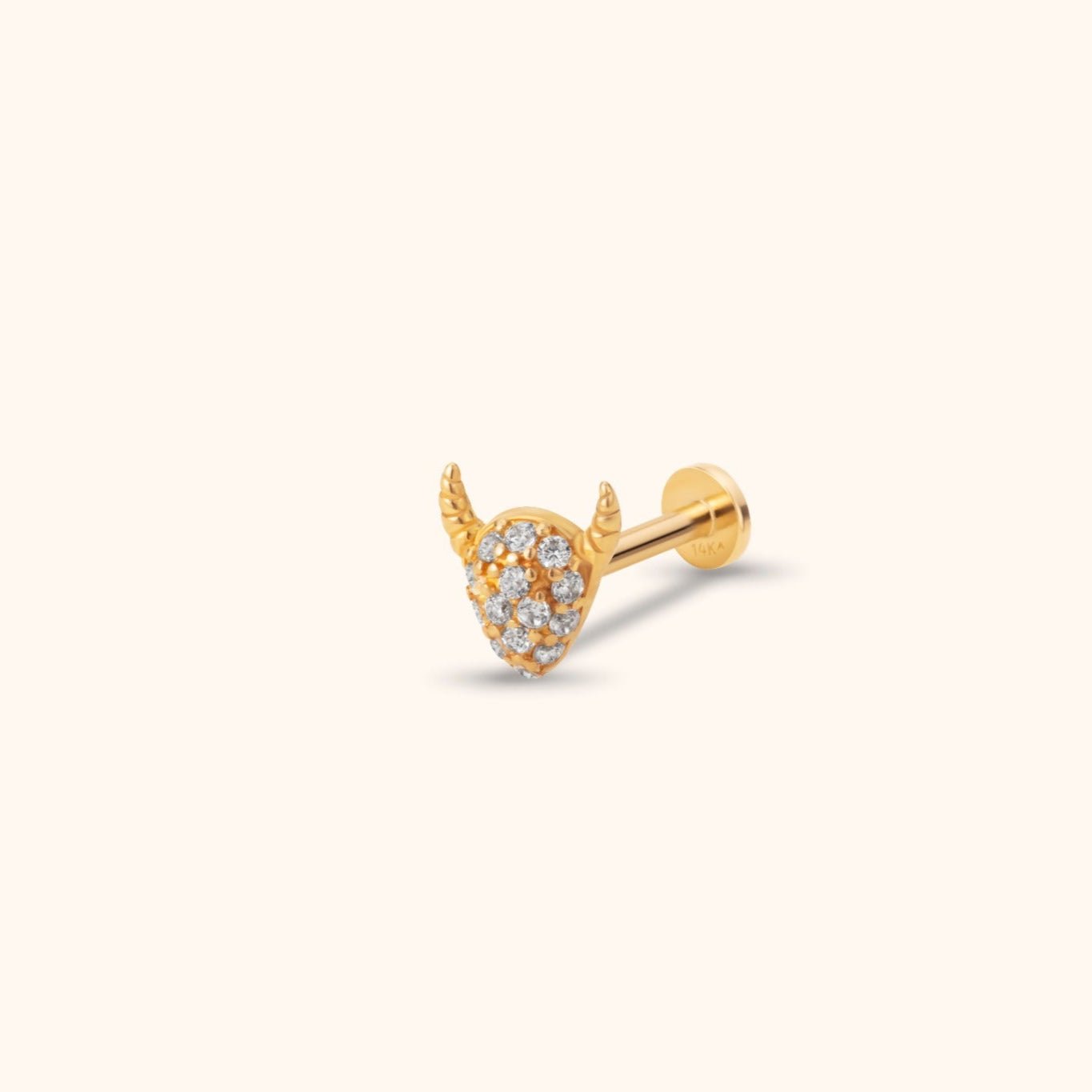 Gold-toned stud with two curved horns, a tapered face set with clear stones, and a round flat back on a cream background.