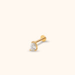 Gold-toned stud with a clear teardrop-shaped faceted center, prong setting and round flat back on a cream background.