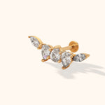 Gold-toned flat-back stud with five clear faceted accents in a curved cluster, shown at an angle on a cream background.