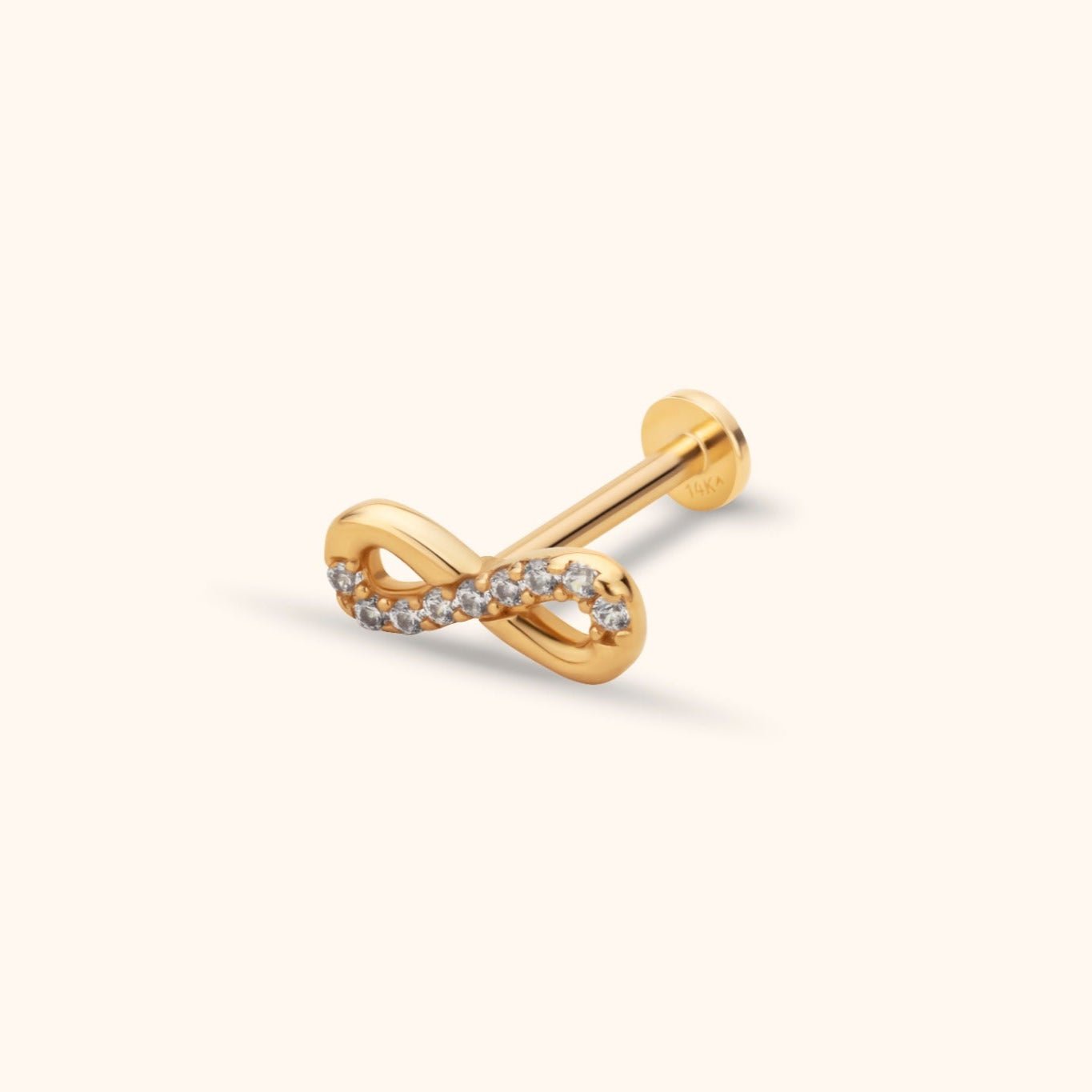Gold-colored infinity stud with a row of clear sparkling accents, a straight post and a round flat back on a cream background.
