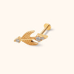 Gold-colored arrow stud with ridged feather details, three clear round accents, and a flat circular back on a cream background.