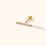 Gold-tone bar stud with a row of clear round stones, a straight post and a flat circular back on a cream background.