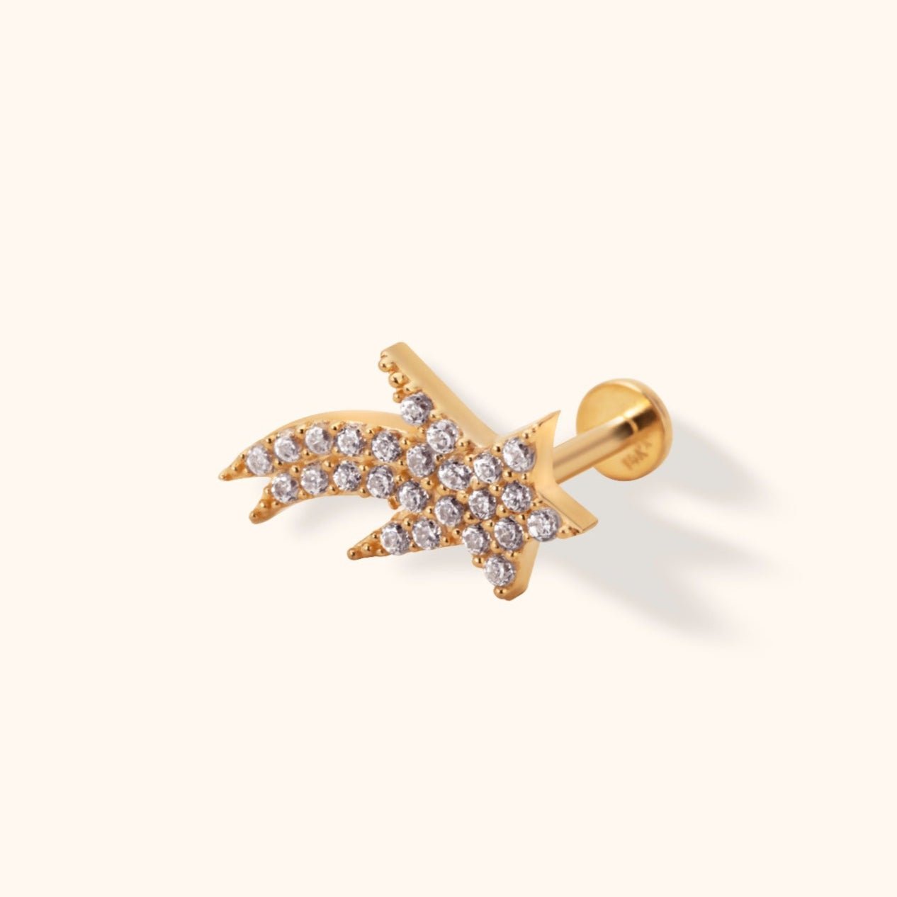 Gold-toned shooting star stud with small clear accents, a straight post and round flat back on a cream background.