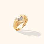 14K yellow gold signet ring with a pavé diamond heart on top, photographed on a neutral background