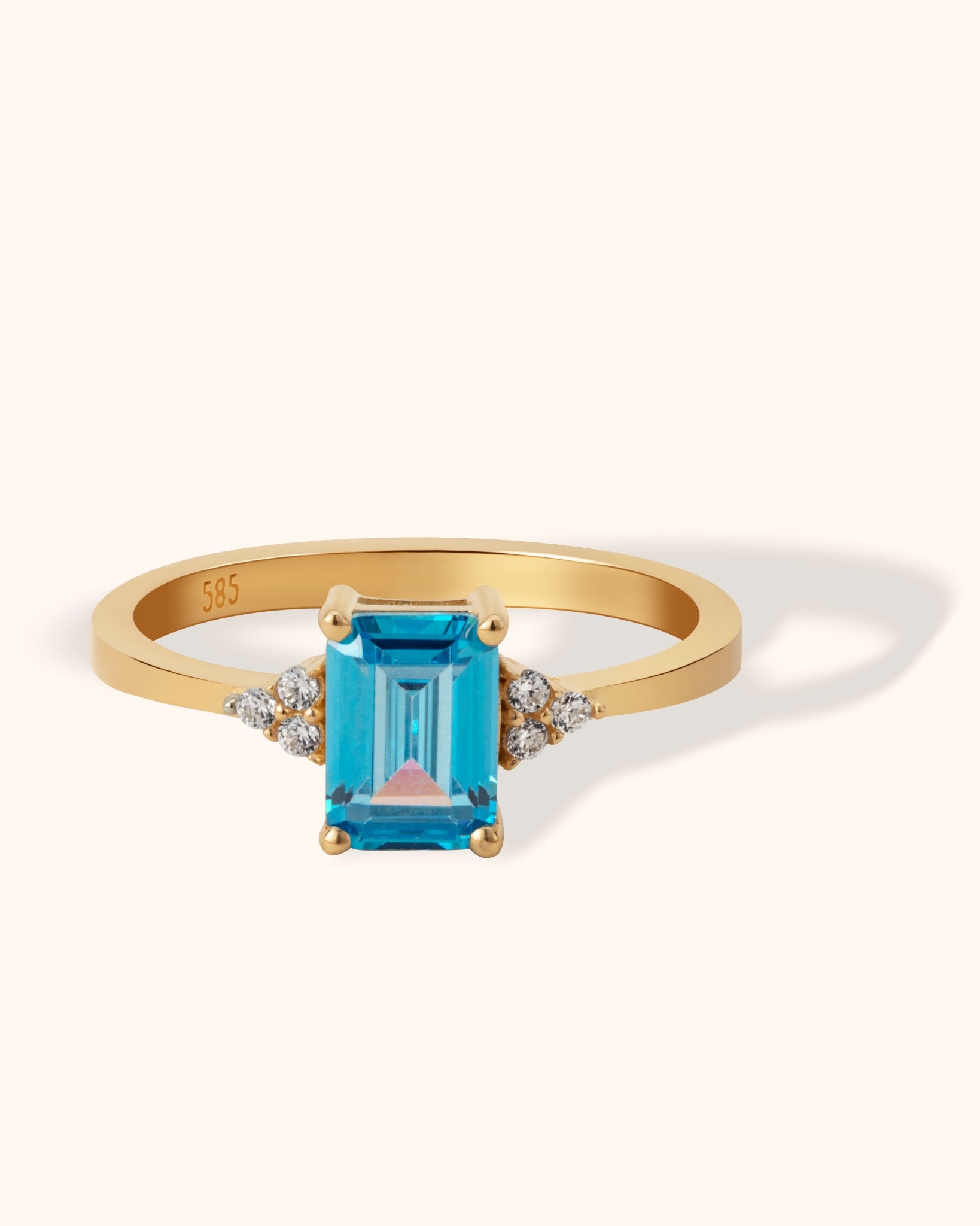 14K gold ring with emerald-cut blue topaz and side diamond clusters