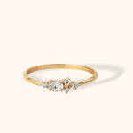 Delicate 14K gold ring featuring an oval-cut center diamond and clustered side stones