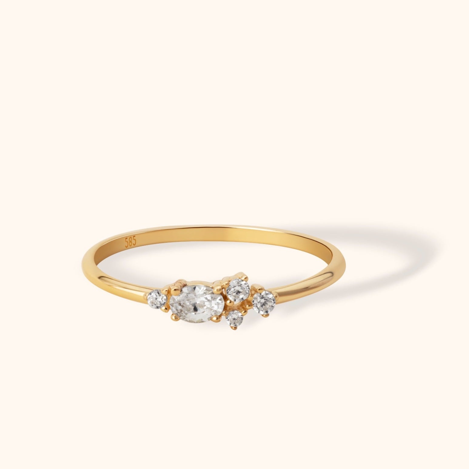 Delicate 14K gold ring featuring an oval-cut center diamond and clustered side stones
