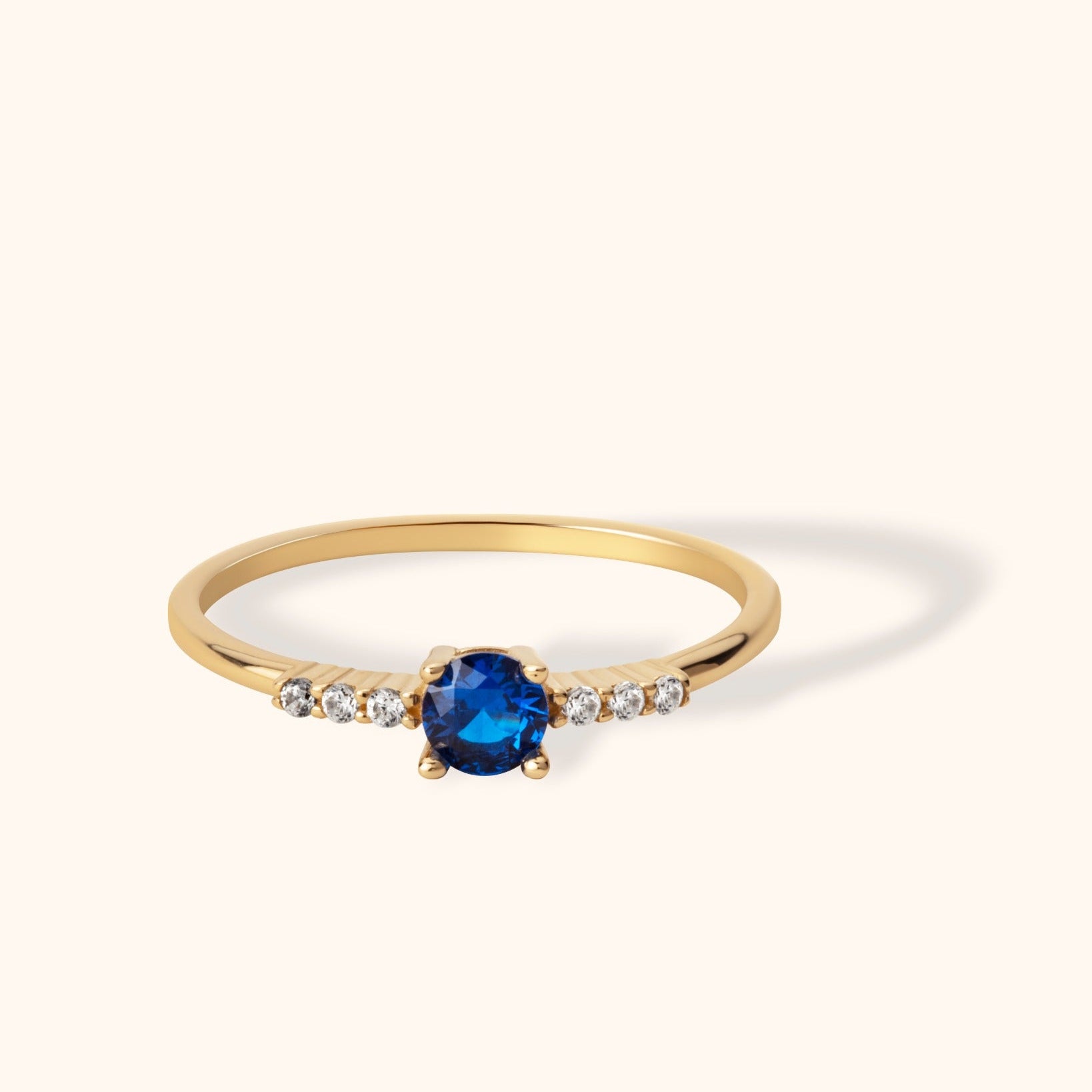Delicate 14K gold ring with round blue sapphire center and diamond side accents
