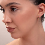 Close-up of model wearing classic small gold hoop earring and minimal gold necklace

