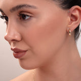 Close-up of model wearing classic small gold hoop earring and minimal gold necklace

