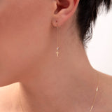 Gold threader earring with cross charm and crystal bead on model's ear


