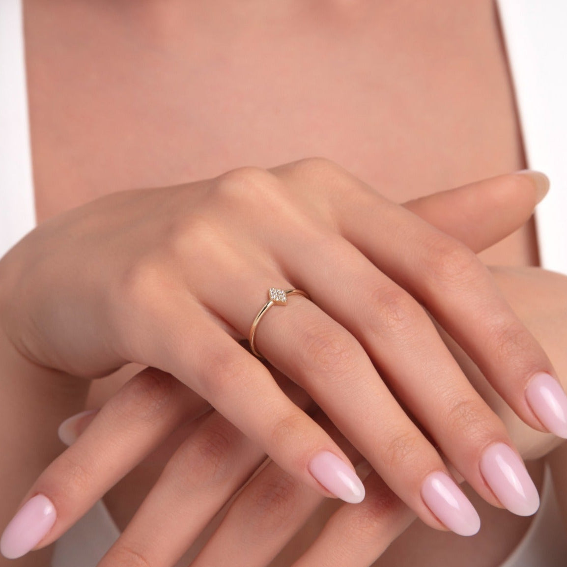 Close-up of a woman's hands wearing a 14K gold ring with a small diamond-shaped head set with micro pave stones, captured from a frontal angle.