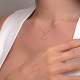 Close-up of a woman's neck wearing a delicate 14K gold lotus flower pendant necklace on a fine chain.