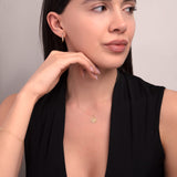 Close-up of a woman wearing a 14K gold lotus necklace and minimalist gold earrings, styled with a deep V-neck black top — showcasing a calm and elegant expression.