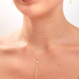 Close-up of woman wearing a 14K gold plated floral pendant necklace with vertical crystal bar and initial letter "A" earrings

