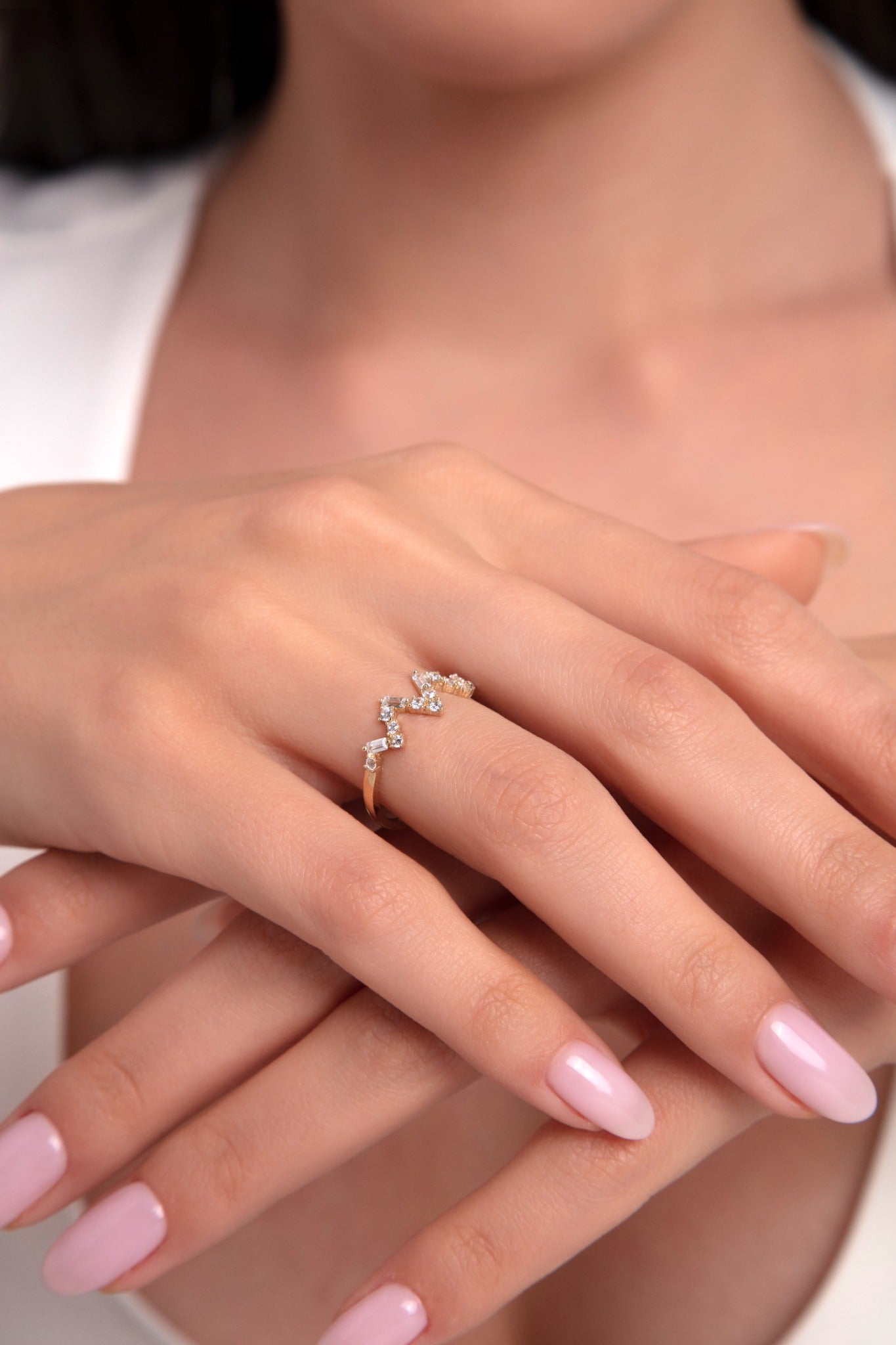 Close-up shot of a zigzag 14K gold ring with cubic zirconia on a woman's finger