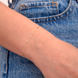 Minimalist gold bead bracelet on wrist with denim background, dainty jewelry close-up

