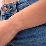 Close-up of a dainty gold chain bracelet on wrist, styled with blue denim jeans

