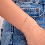 Minimalist gold paperclip chain bracelet on wrist with denim jeans background

