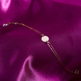 14K gold bracelet with a personalized round disc charm on a double chain, presented on a purple satin background