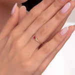 Elegant woman's hands showing a delicate 14K gold ring with a pink gemstone and small white stones, styled with soft pink manicured nails.