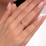 Elegant woman's hands showing a delicate 14K gold ring with a pink gemstone and small white stones, styled with soft pink manicured nails.