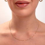 Gold faceted disc chain necklace on model's neck, minimalist jewelry with light-catching sparkle

