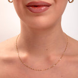 Gold faceted disc chain necklace on model's neck, minimalist jewelry with light-catching sparkle

