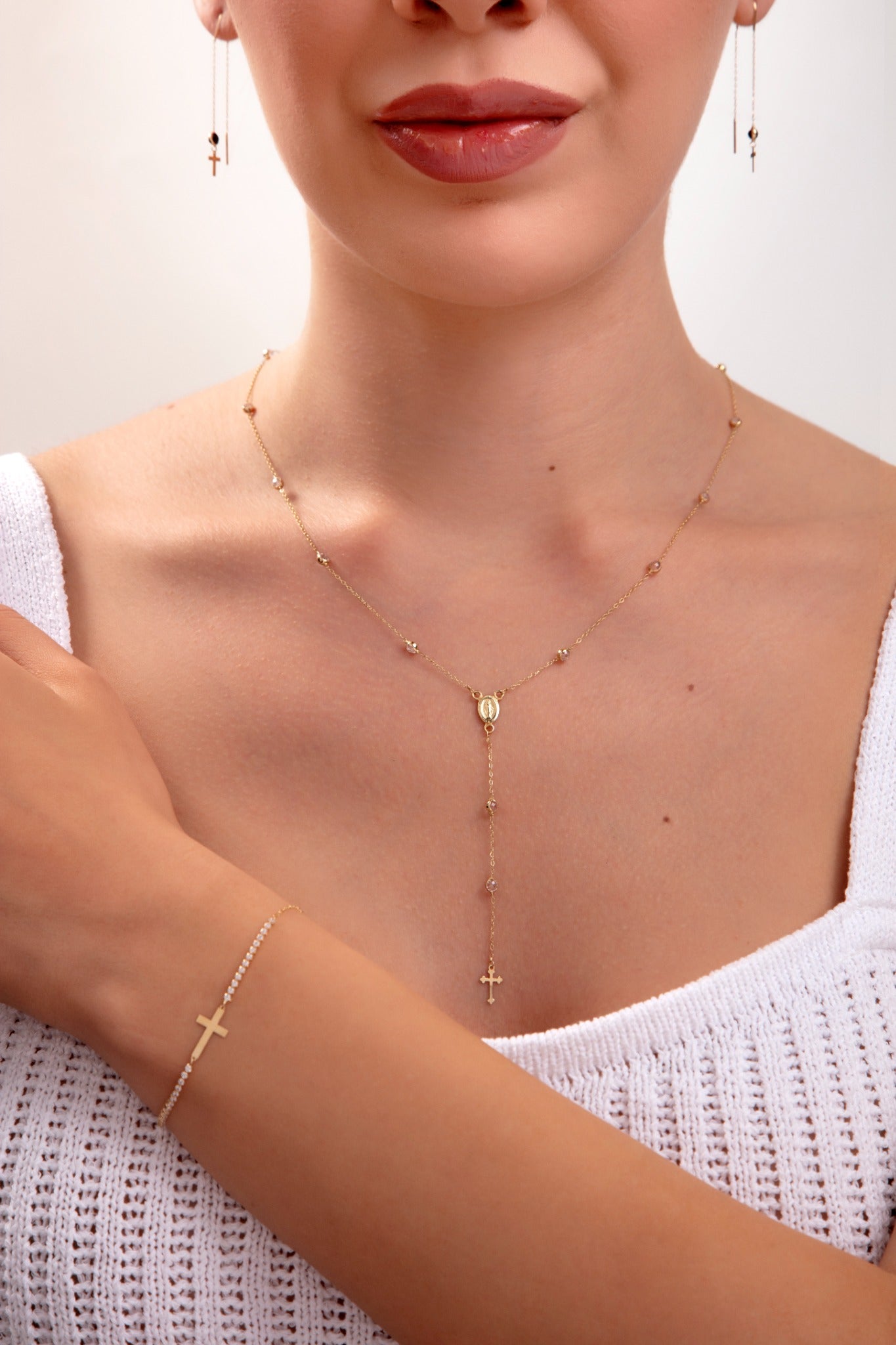 Model wearing a 3-piece 14K gold plated faith jewelry set with rosary necklace, cross bracelet, and matching earrings

