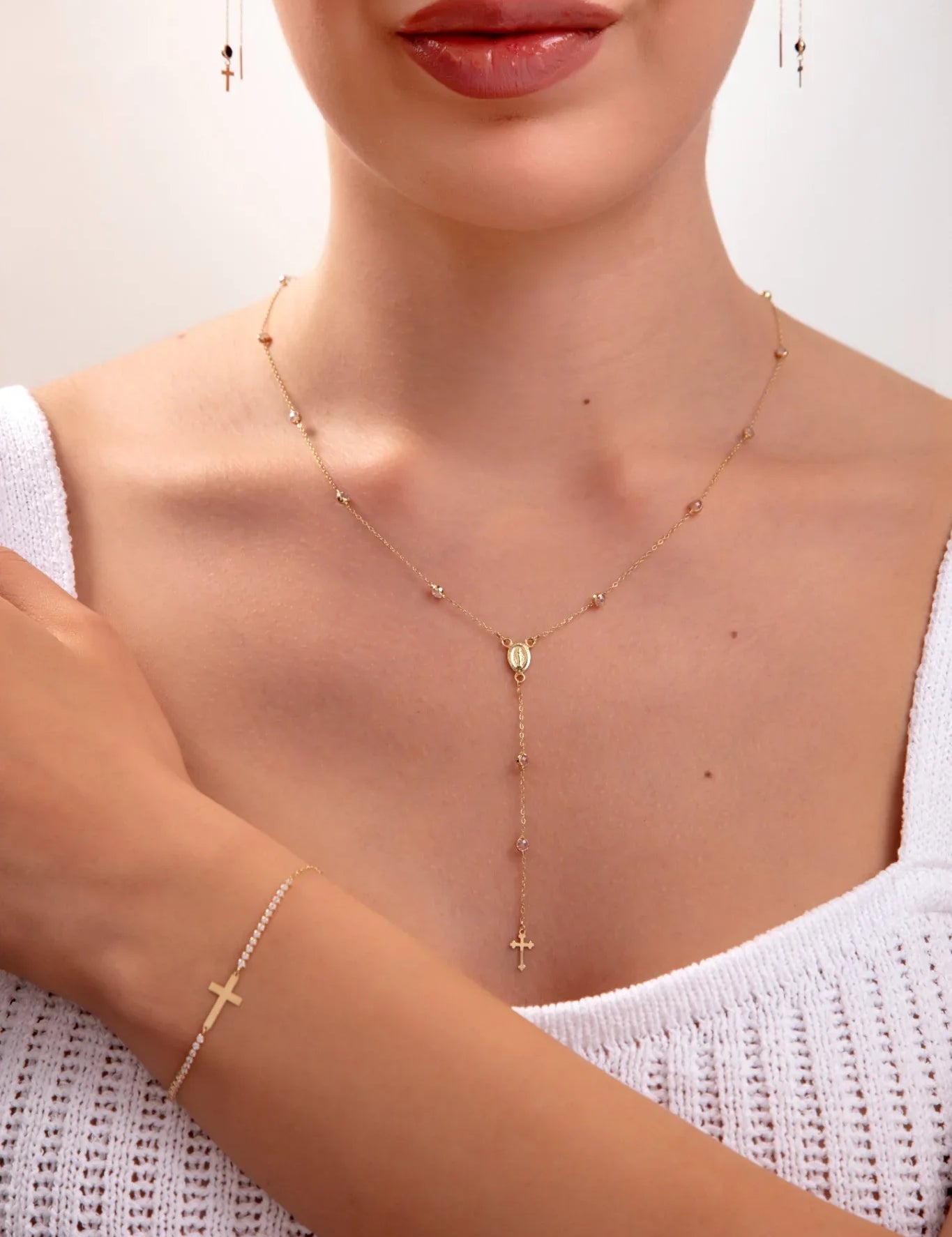 Model wearing a 3-piece 14K gold plated faith jewelry set with rosary necklace, cross bracelet, and matching earrings

