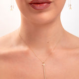 Woman wearing 14K gold plated floral drop necklace with crystal bar and initial threader earrings, model shows the letter "A"

