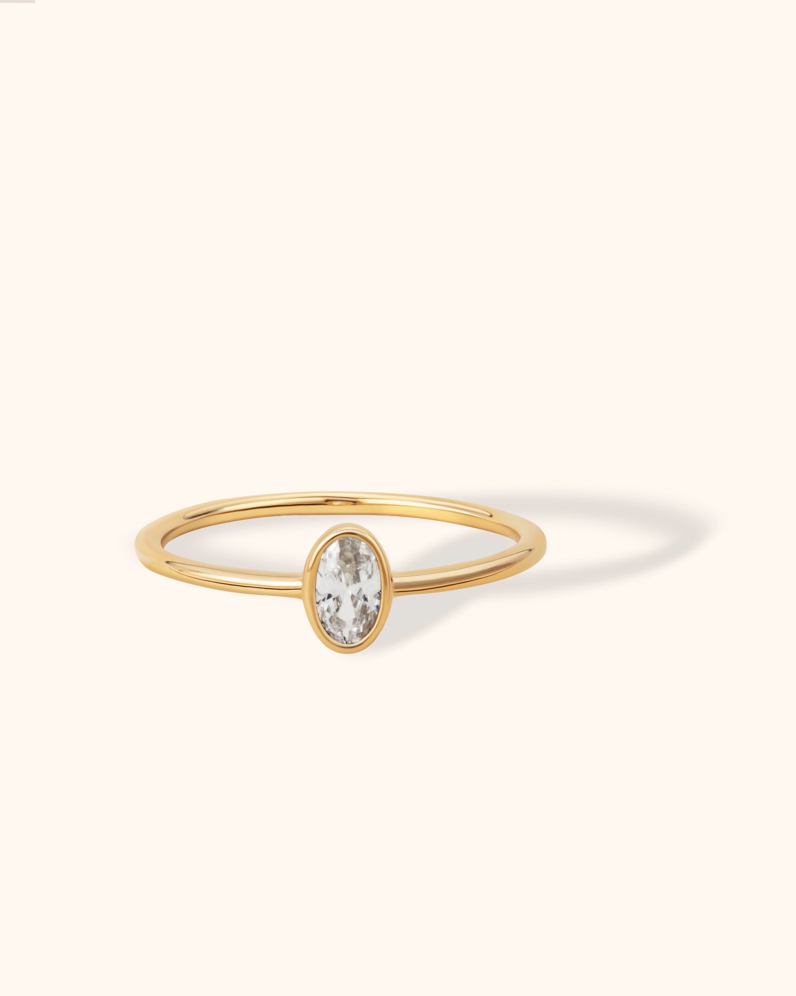 Minimalist 14K gold ring with oval white sapphire bezel setting