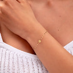 close-up of gold disc bracelet on model's wrist

