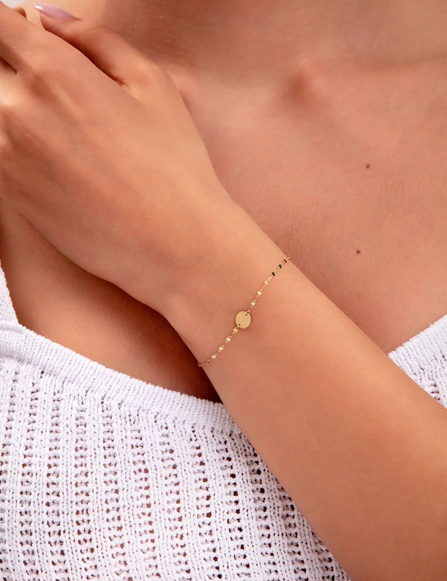 close-up of gold disc bracelet on model's wrist

