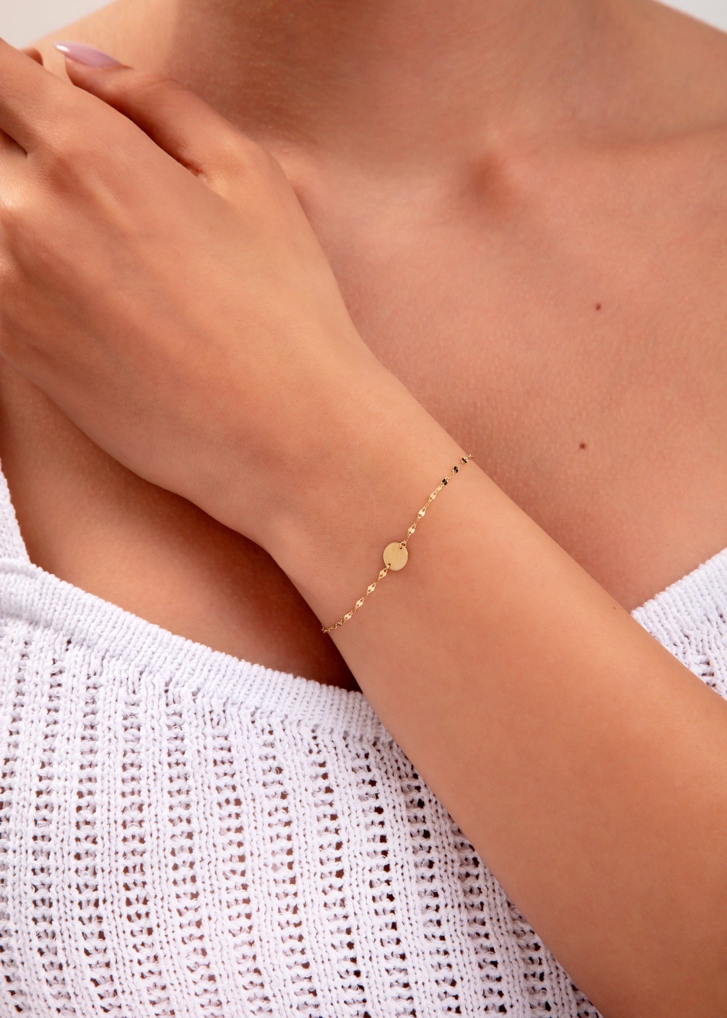 close-up of gold disc bracelet on model's wrist

