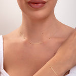 Model wearing matching 14K gold plated bead station necklace and bracelet set with white knit top

