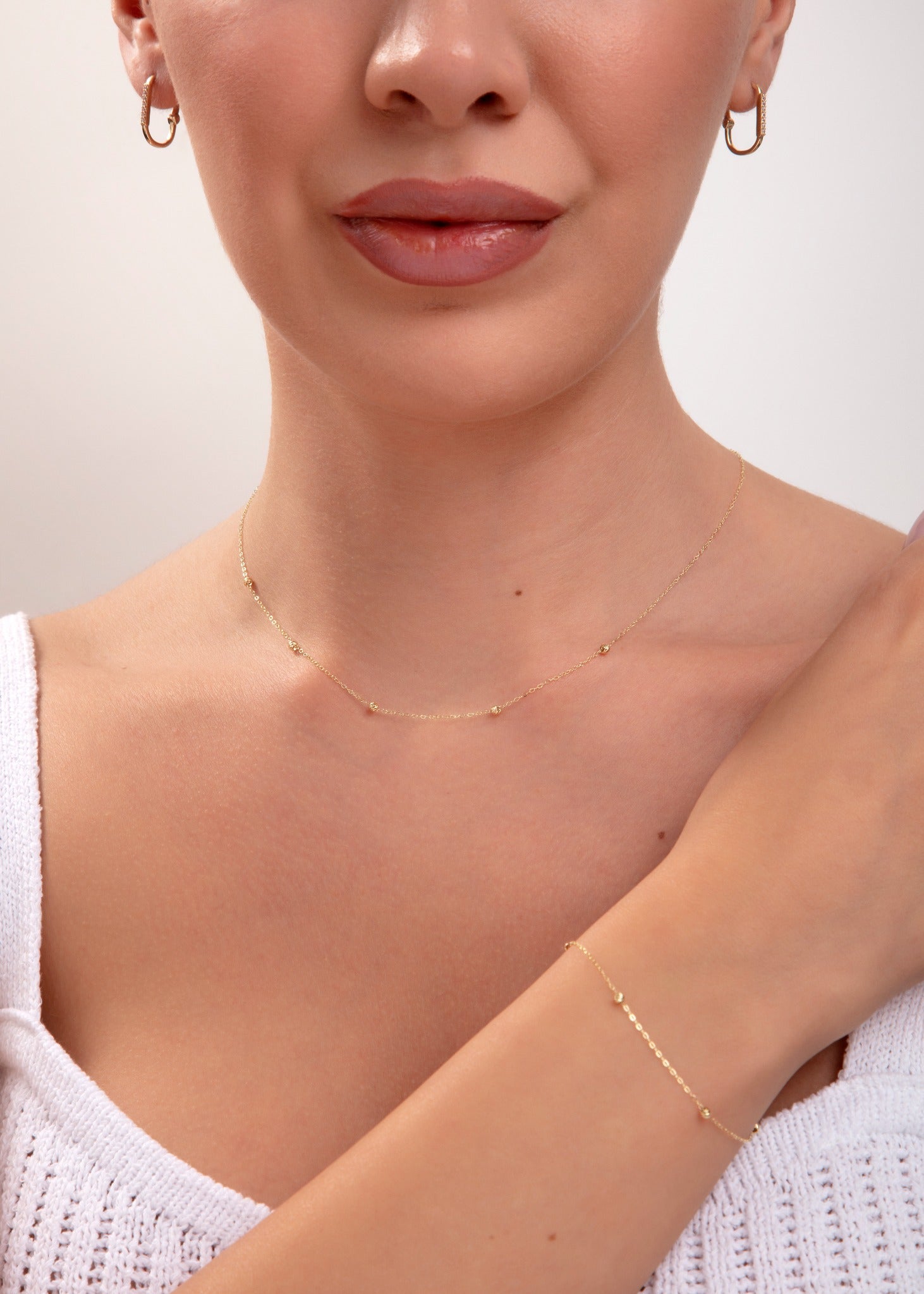 Model wearing matching 14K gold plated bead station necklace and bracelet set with white knit top

